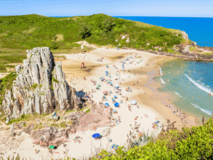Playa de arena con acantilados y vegetación, ideal para relajarse y disfrutar del mar en Uruguay.