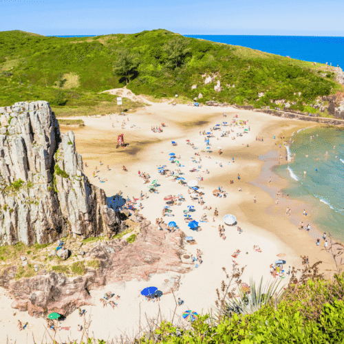 Playa de arena con acantilados y vegetación, ideal para relajarse y disfrutar del mar en Uruguay.