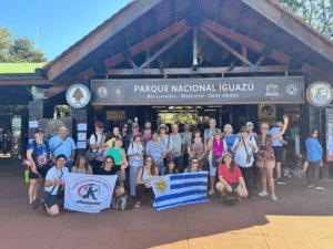 Group of travelers holding Uruguayan flag and banner at Iguazú National Park.