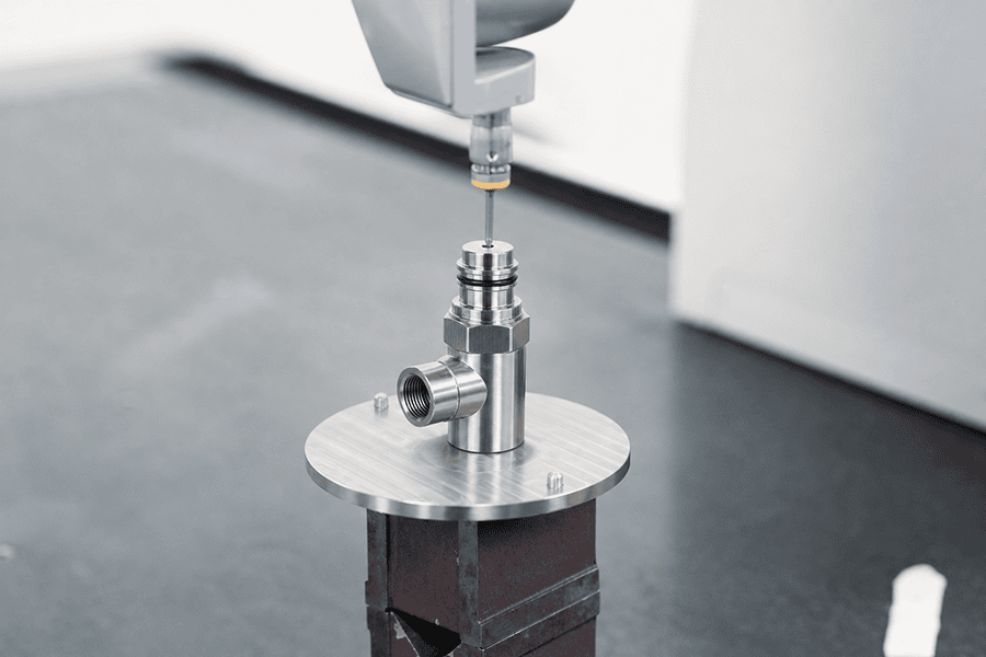 CMM inspection of a 316L stainless steel fluidic valve body in a temperature-controlled room, part of a precision machining supplier tolerance verification workflow with datum-referenced probing