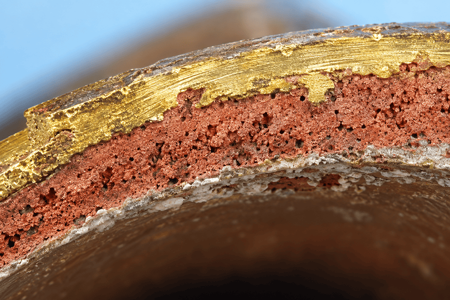 Cross-section of a dezincified brass valve showing porous copper-rich residue beneath the surface