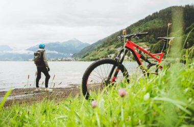 Mountainbike am Flussufer mit Bergpanorama im Hintergrund.