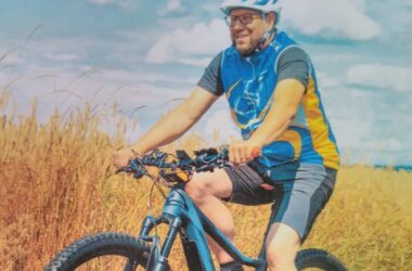 Mann beim Mountainbiken auf Feldweg, trägt Helm und Sportkleidung.