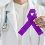 Purple awareness ribbon held by a medical professional, symbolizing health advocacy and support for medical causes.