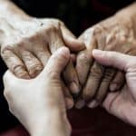Elderly hands holding younger hand, symbolizing care, compassion, and legal support for senior issues, family law, or estate planning by Farr Law Firm.