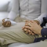 hand holding couple siting on sofa