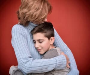 Happy and smiling young boy with closed eyes hugging his lovely mother