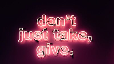 Großes Neon-Schild mit dem Text "don't just take, give." in Pinkleucht.
