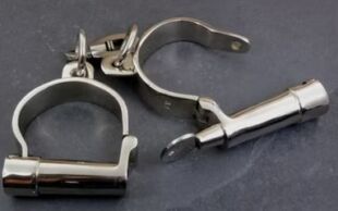 Dieses Bild zeigt ein Set aus Metallhandschellen, einem Knebel und einem weiteren Fessel-Element, die f&uuml;r BDSM-Aktivit&auml;ten verwendet werden. Die Gegenst&auml;nde sind aus Edelstahl gefertigt, was sie langlebig und hygienisch macht. Das Set ist auf einem dunklen Hintergrund platziert und vermittelt ein Gef&uuml;hl von Sicherheit und Kontrolle f&uuml;r einvernehmliche erotische Spiele.