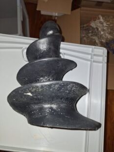 Das Bild zeigt einen kunstvoll gestalteten schwarzen Steinschmuck in Form eines spiralf&ouml;rmigen Fistwerks, der auf einem wei&szlig;en Untergrund liegt. Das Schmuckst&uuml;ck hat eine glatte Oberfl&auml;che mit nat&uuml;rlichen Texturen und ist ein einzigartiges Handwerkskunstst&uuml;ck, das durch seine organische Form und das dunkle Material besticht. Es ist ein Symbol f&uuml;r St&auml;rke und Naturverbundenheit, ideal f&uuml;r Sammler und Liebhaber von handgefertigtem Schmuck.