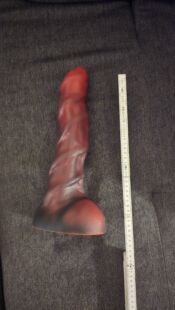 Hochwertiger, realistisch gestalteter roter Dildo mit spiralf&ouml;rmiger Textur, ideal f&uuml;r intime Zwecke. Das Bild zeigt das Produkt neben einem Ma&szlig;stab, um die Gr&ouml;&szlig;e zu verdeutlichen, auf einem schwarzen Stoffhintergrund.