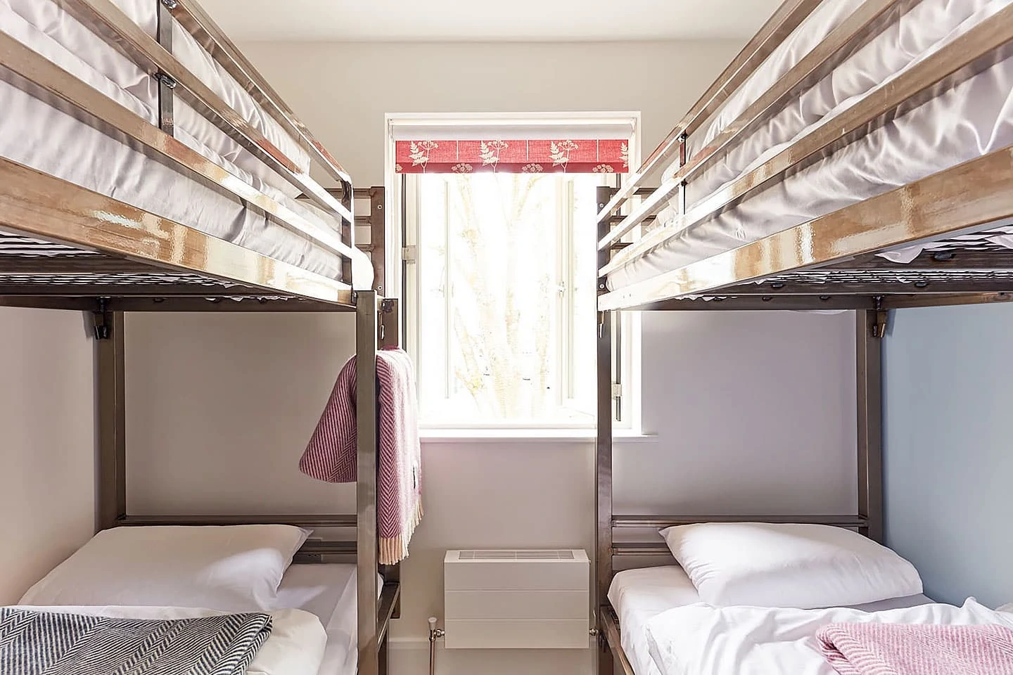 Bunk beds in a modern hostel room at The Barrel Store, featuring wooden frames and cosy bedding.