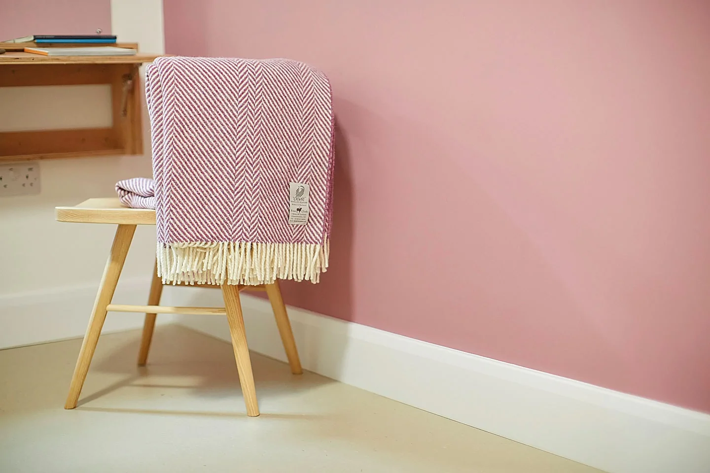 Chic wooden chair with pink and white patterned throw blanket in a modern interior.