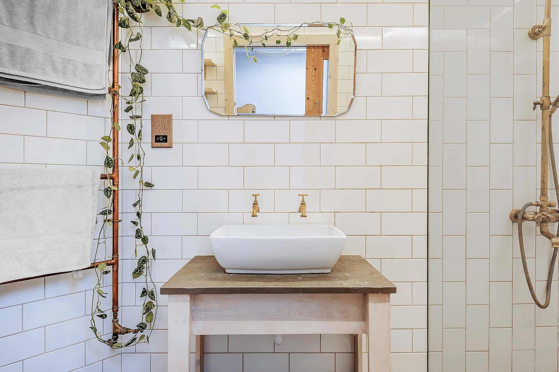 Elegant country house bathroom with white subway tiles and rustic wooden accents.