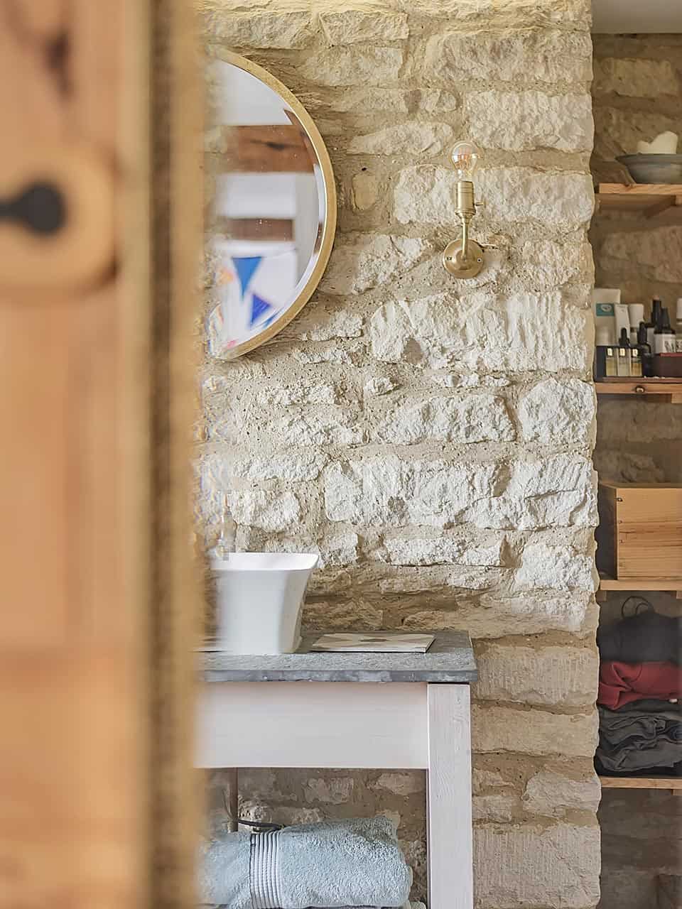Elegant stone wall with modern sink and brass wall light.