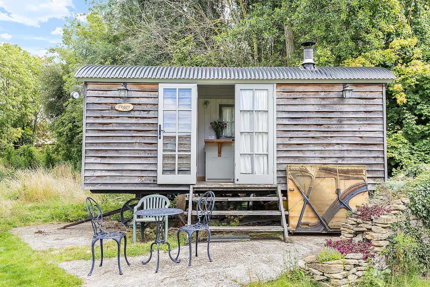 Beautiful rustic garden shed with inviting outdoor seating area and lush greenery.