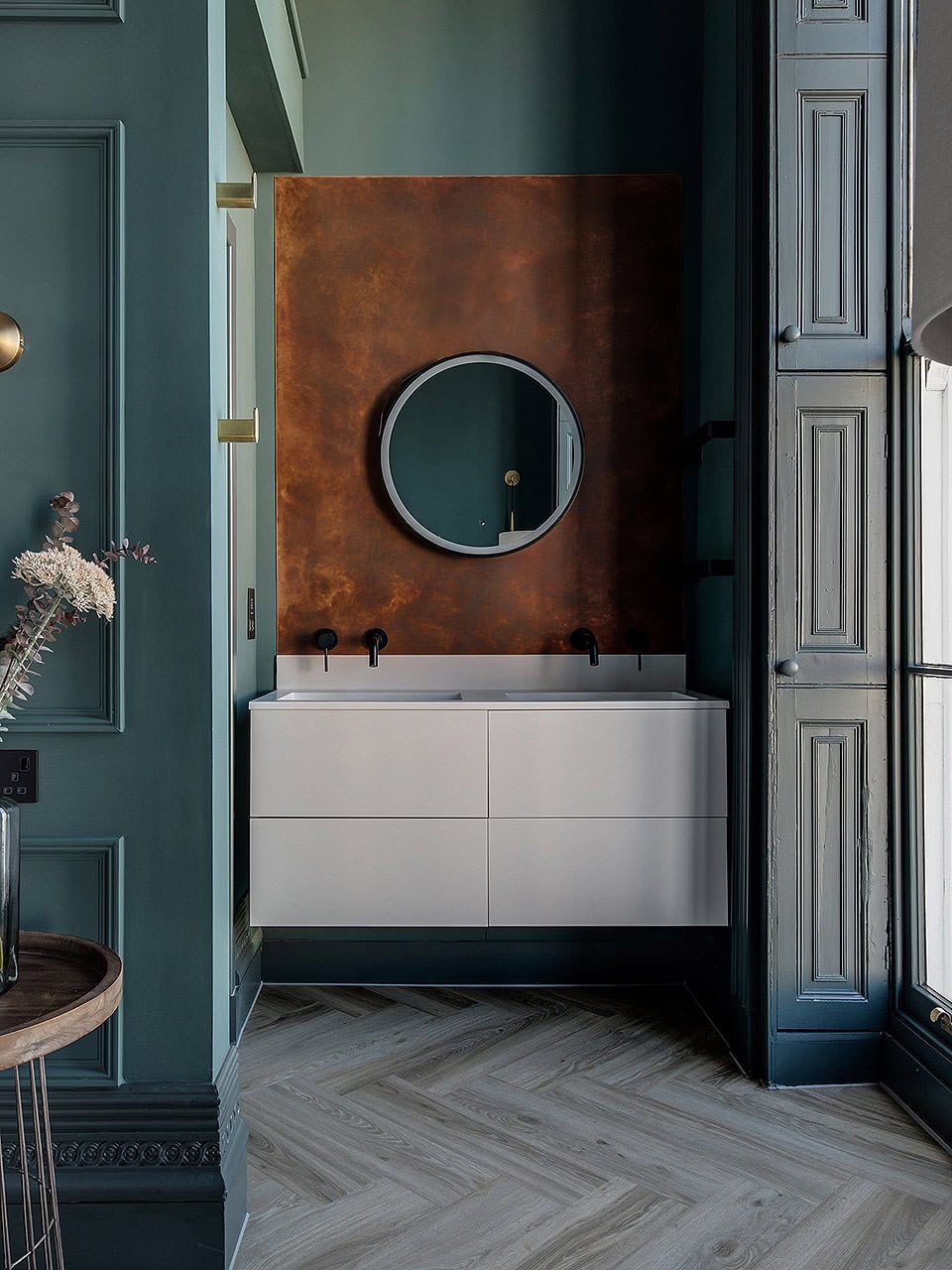 Modern bathroom vanity with round mirror and double sink at Neptune Apartments.