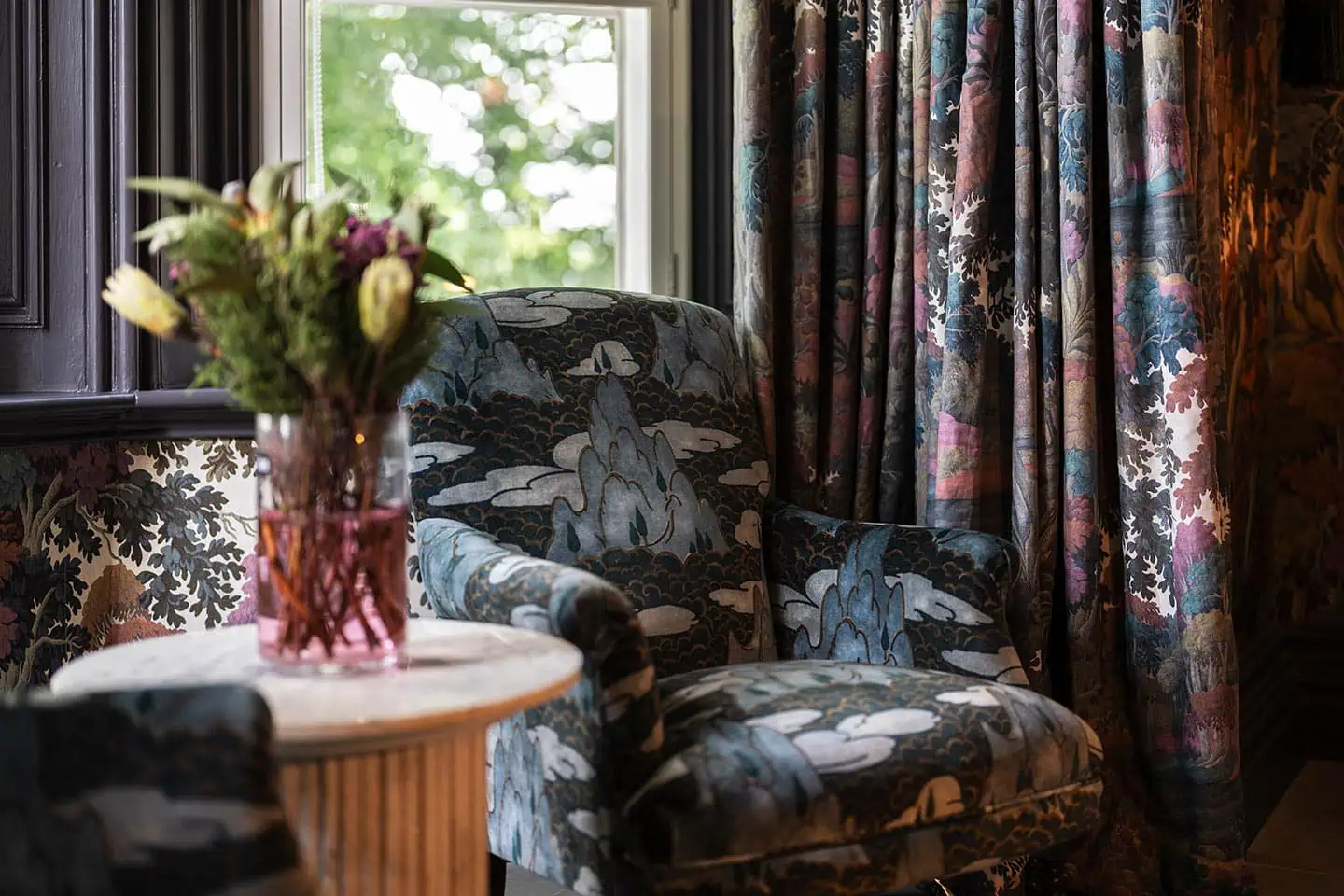 Luxurious drawing room with vintage floral-patterned armchair and ornate curtains.