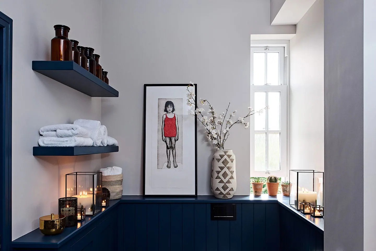 - A stylish shower room featuring modern decor, candles, and potted plants by the window.