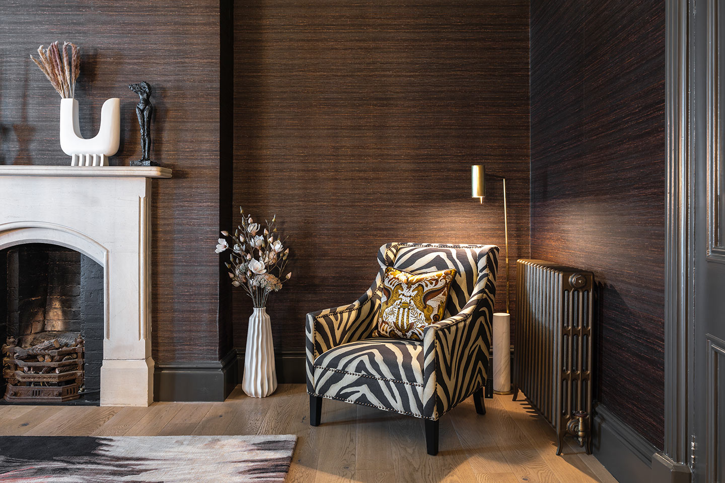 Elegant master bedroom with zebra print armchair and warm lighting.