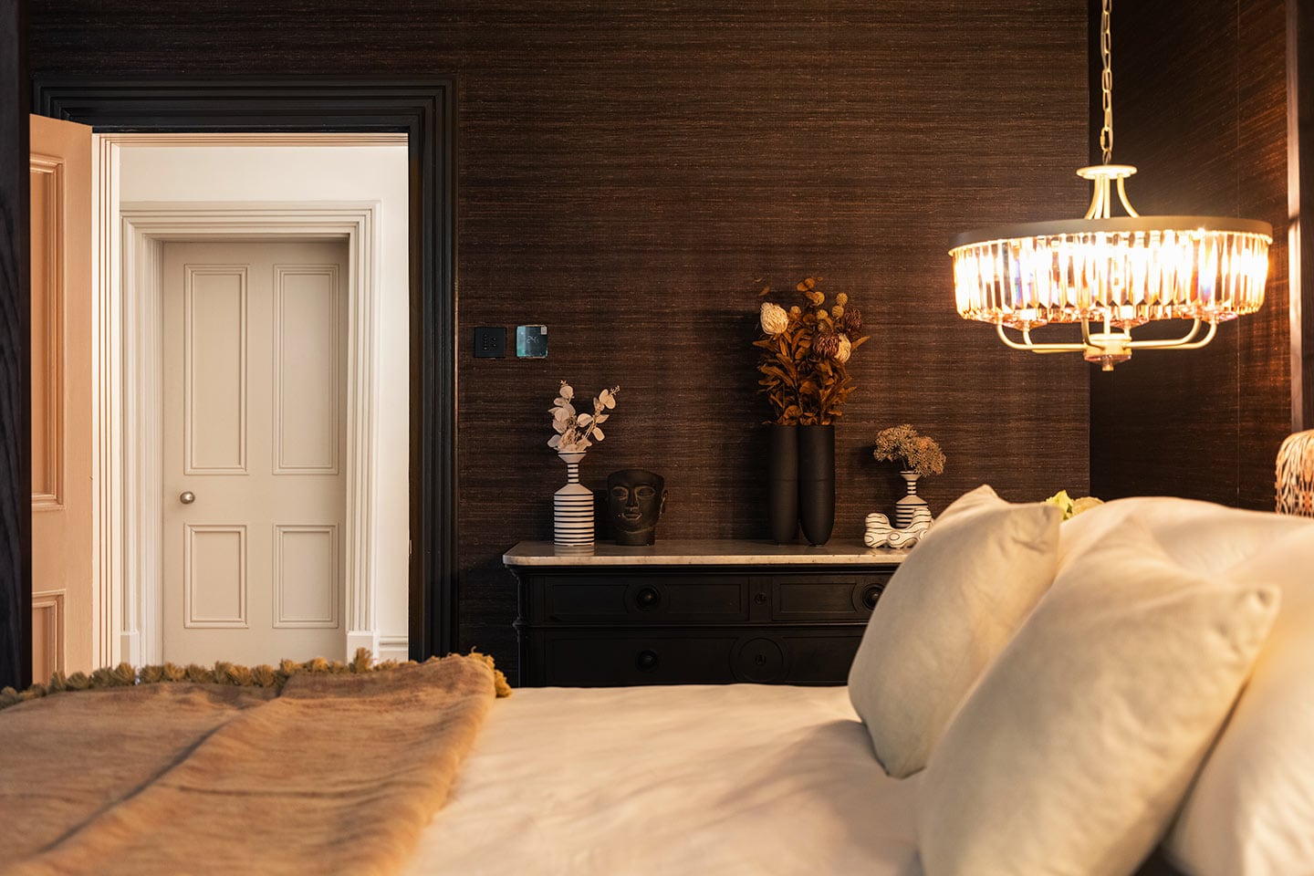 Luxurious master bedroom featuring dark wood walls, stylish decor, and ambient lighting.