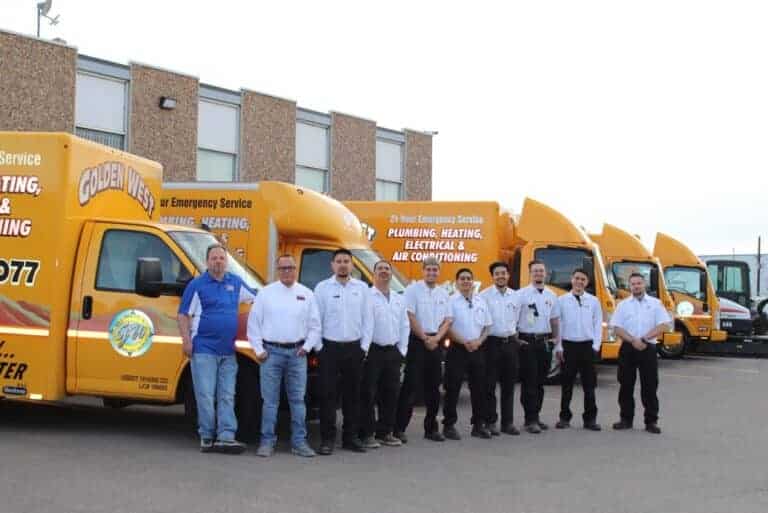 A group of ten service technicians stands in front of a row of yellow company vans marked for plumbing, heating, electrical, and air conditioning services—showing the dedicated team behind our about us story.