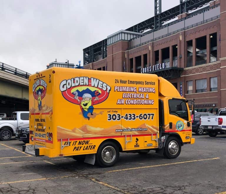 A yellow Golden West service truck with plumbing, heating, electrical, and air conditioning ads is parked outside Coors Field.