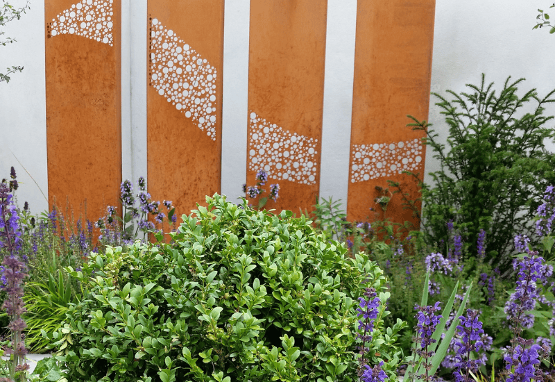 Corten decorative panels for landscape and design with lots of green foliage and flowers