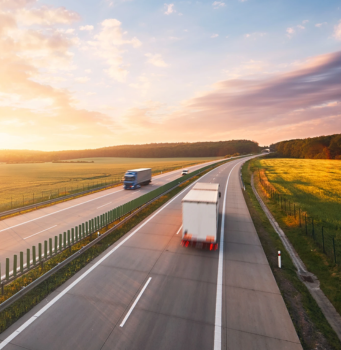 Moving truck driving on highway during sunset in rural landscape.