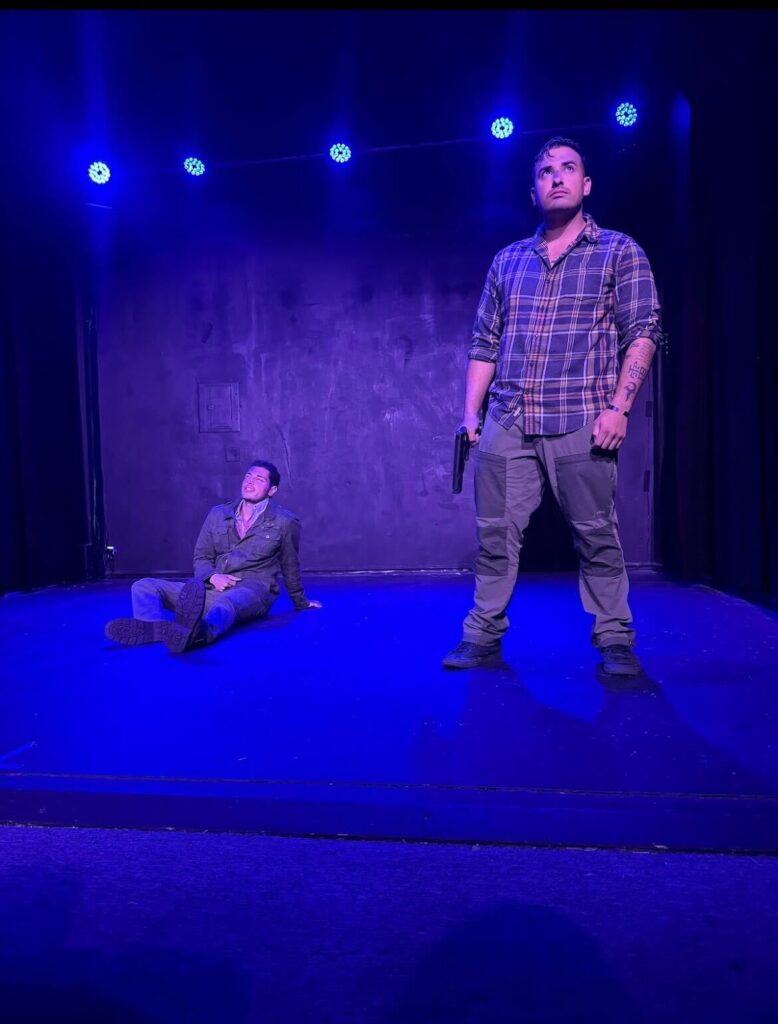 Two actors on stage under blue lights.