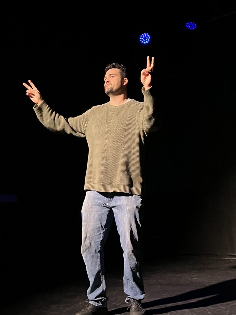 Person on stage performing peace sign gesture