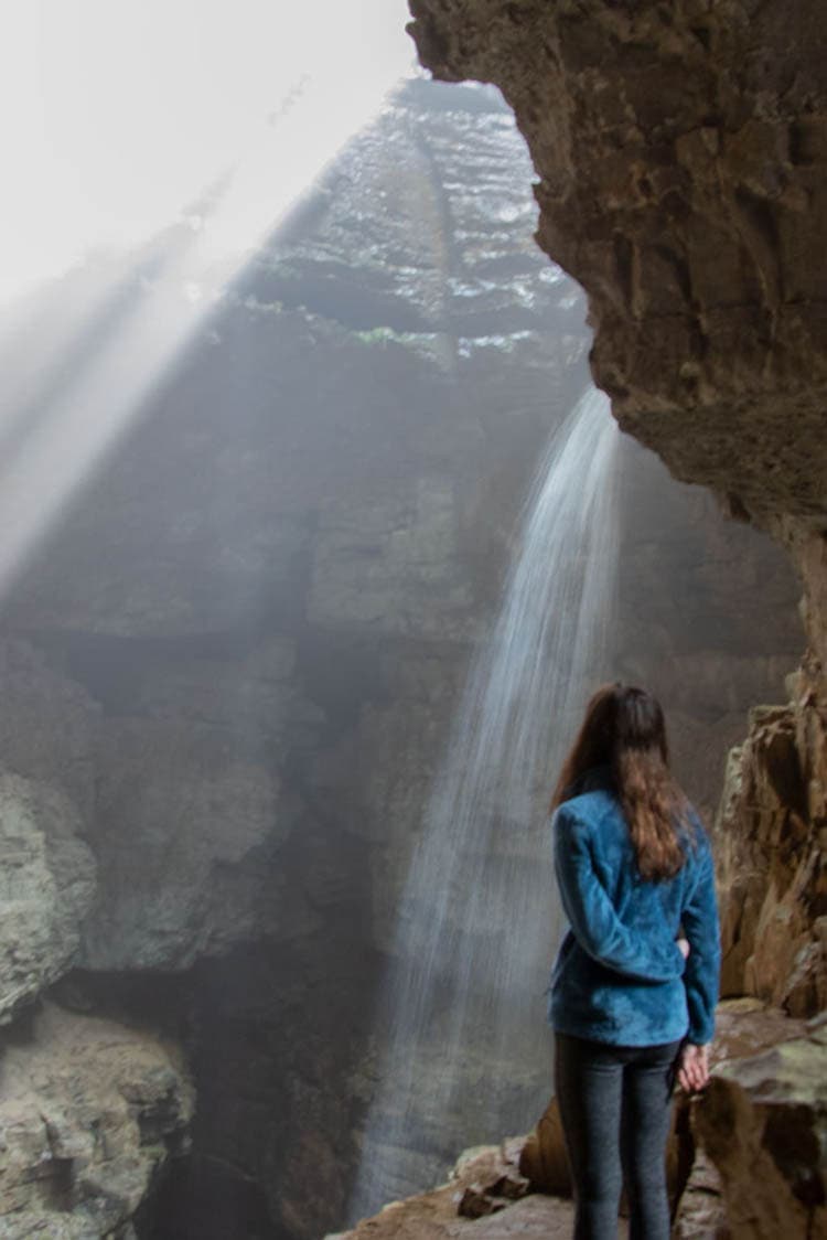 Inside Stephens Gap Cave looking at a waterfall and beam of light