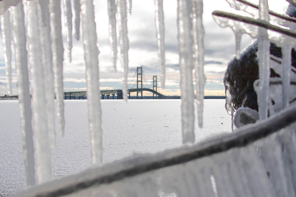 A Stress-Free Family Road Trip Packing List A view of Michigan's Mackinac Bridge in the winter. Icicles frame the bridge.