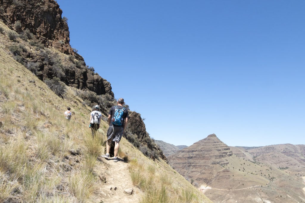 17 Best Day Hikes in Oregon You Don’t Want to Miss (Dog & Family-Friendly) Hiking up to see Blue Basin from above. People high up on a mountain hiking a narrow trail along the edge of the mountain.