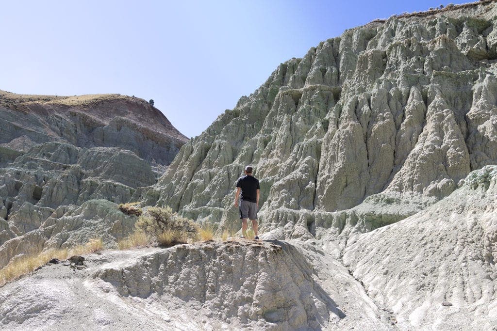 17 Best Day Hikes in Oregon You Don’t Want to Miss (Dog & Family-Friendly) A man standing and looking at the Blue Basin in Oregon. Just hiked Island in Time Trail.