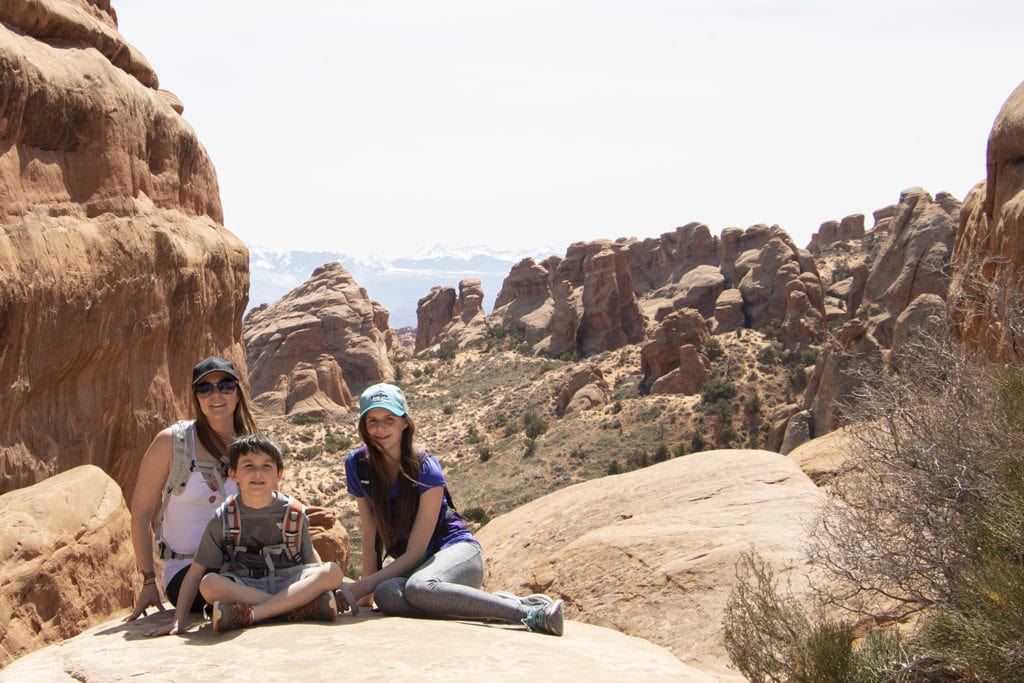 Discover the Funnest National Parks for Kids Family stopped for a photo to take in the view on the way to Double O Arch in Arches National Park.