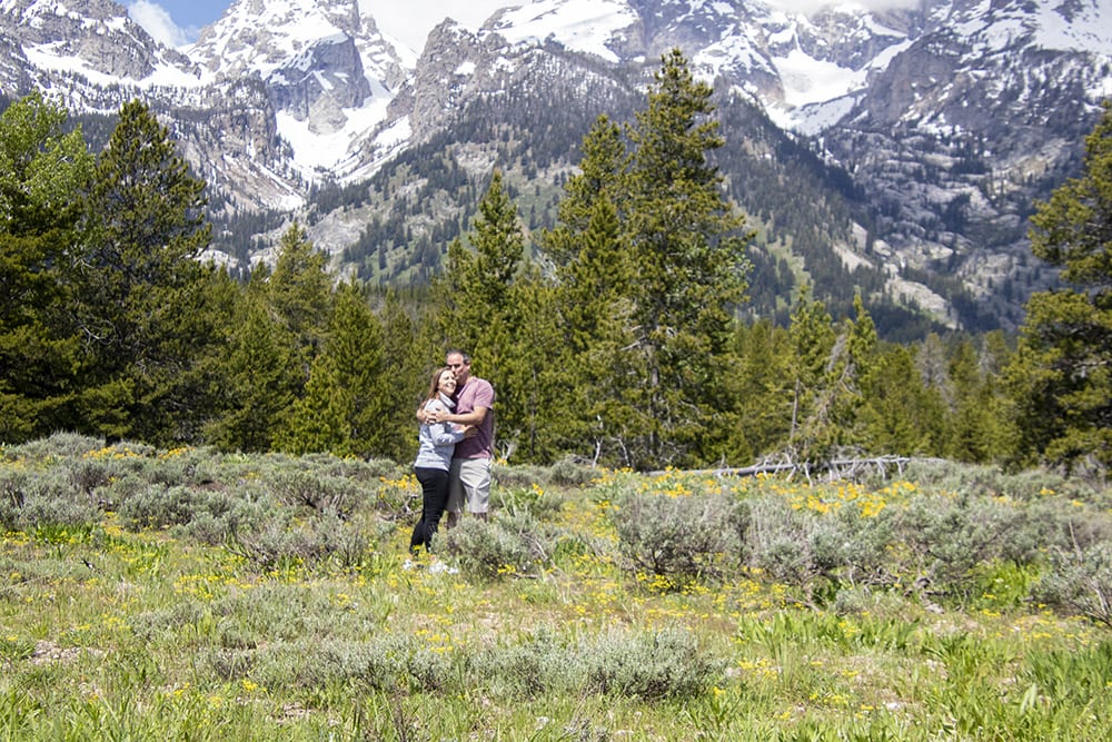 Epic Adventure Quotes For Instagram A couple standing in wildflower field in front of the Grand Teton mountains