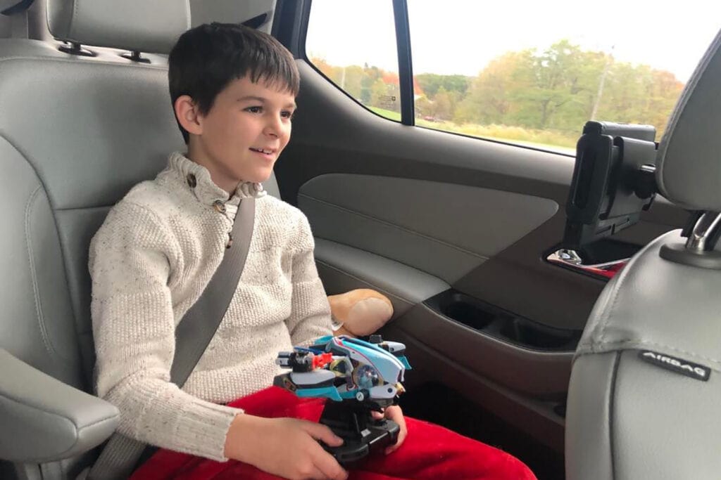 A Stress-Free Family Road Trip Packing List A boy is sitting in a car playing the Nintendo Switch. He is playing the game Starlink.