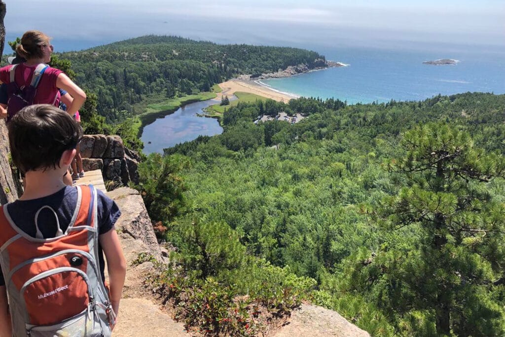 Best Hikes in Acadia National Park + Tips People standing along a skinny cliffside trail in Acadia, one of the best hikes in Acadia National Park.