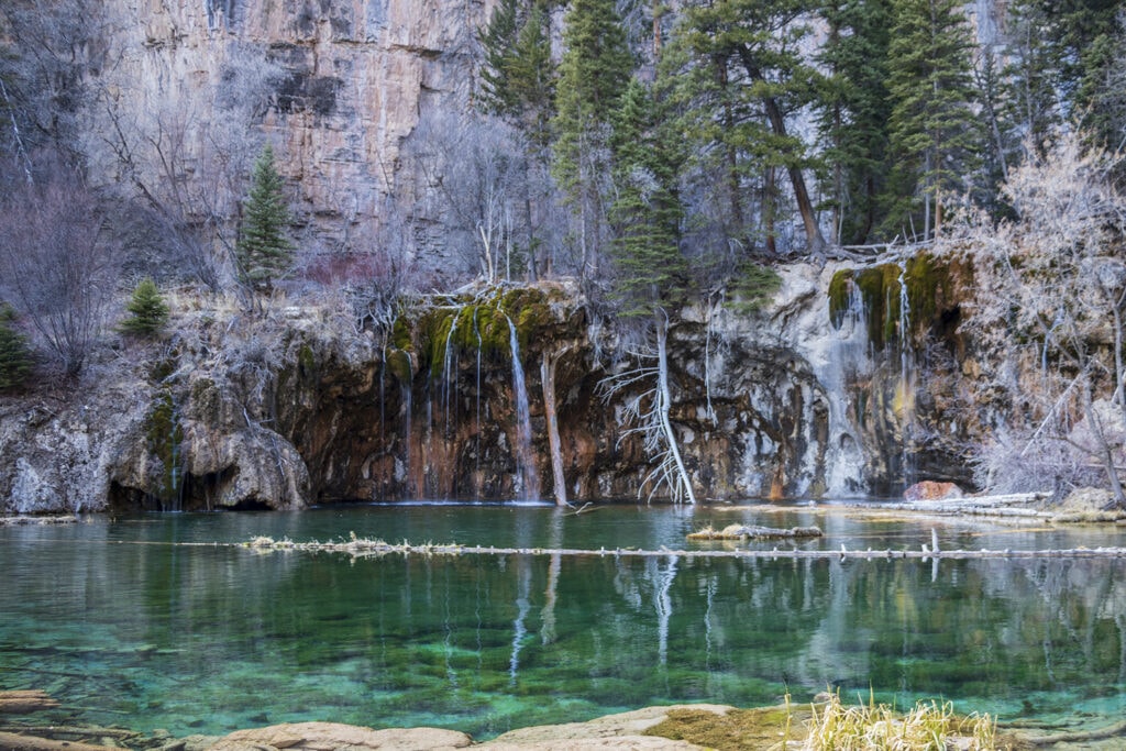 Hiking Hanging Lake in Colorado – The Ultimate Guide A picture of turquoise colored hanging lake and the mossy bridal veil falls flowing into the lake.