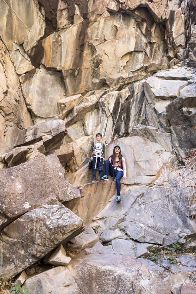 Hiking Hanging Lake in Colorado – The Ultimate Guide Kids resting on the rocky canyon walls hiking to Hanging Lake.