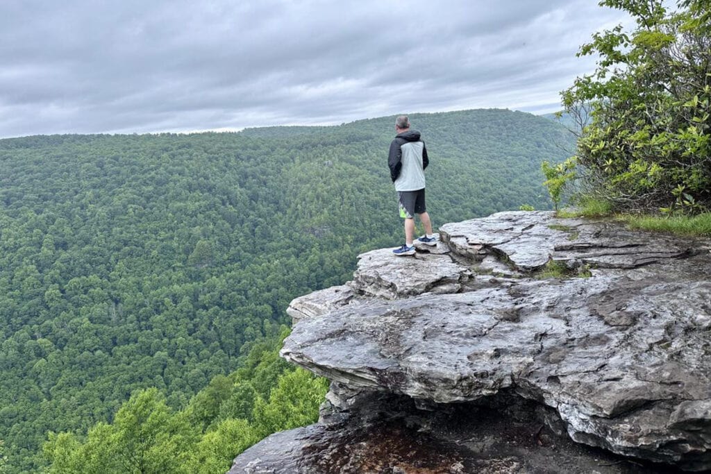 Blackwater Falls State Park Guide: Trails & Top Sights Man standing on large rock taking in the views of Lindy Point in Blackwater Falls WV