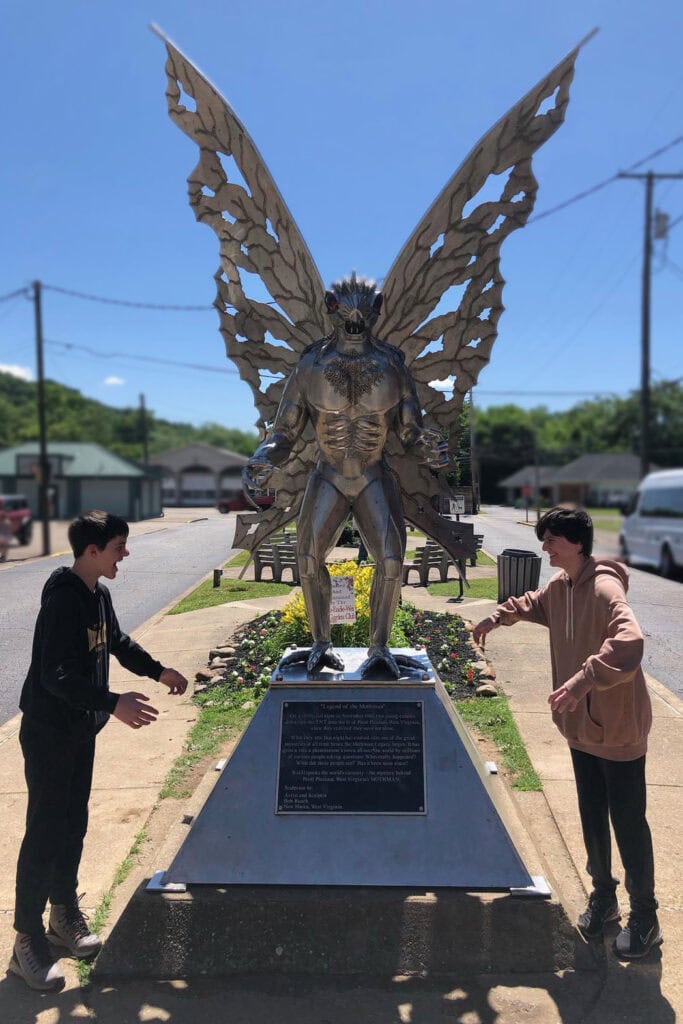Is the Mothman Museum Worth Visiting? Teenagers posing playfully with the Mothman statue in Point Pleasant, West Virginia