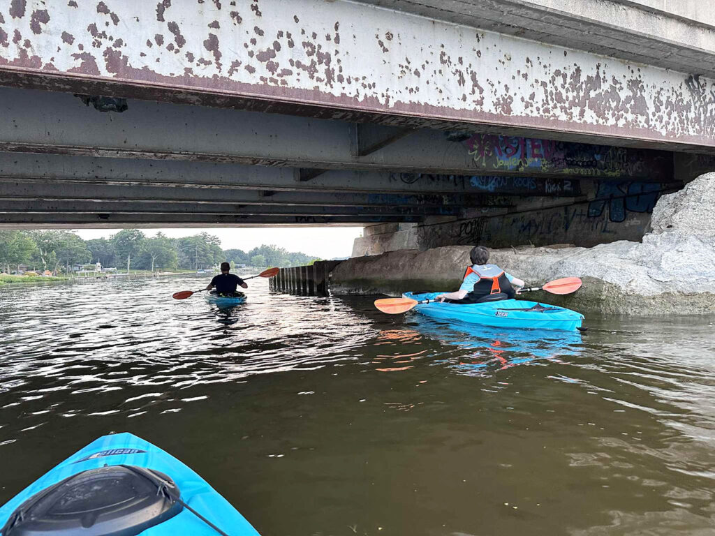 Kayaking under a bridge — a favorite summer bucket list idea for families.