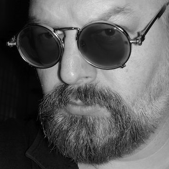Close-up of a man wearing stylish sunglasses and a beard, emphasizing sophistication and style.