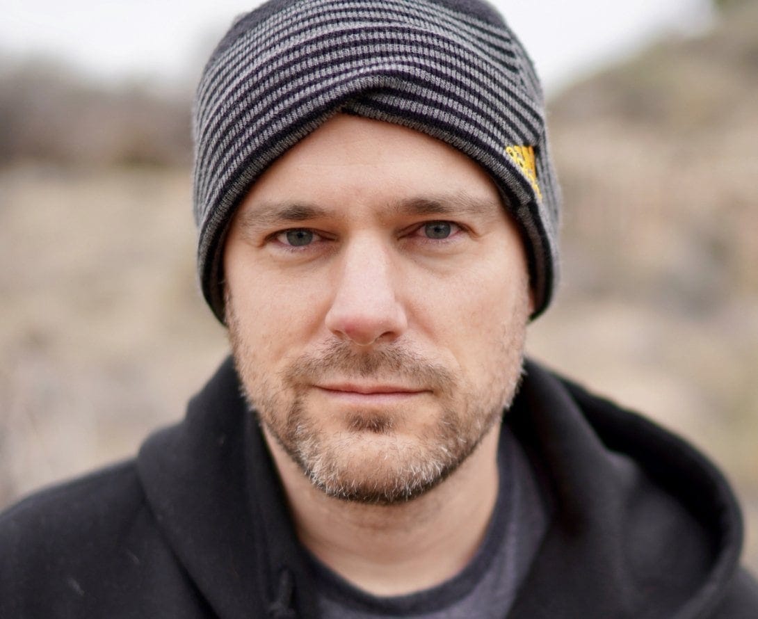 Close-up of a man in a beanie, outdoor setting, rugged appearance, representing Hero Initiative support and charity.