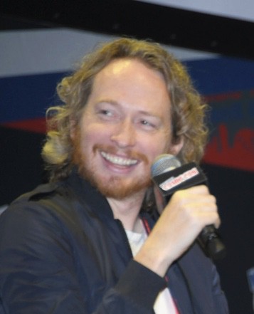 Portrait of smiling man holding microphone at hero event, charity, advocacy.
