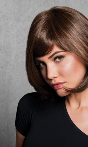Woman with sleek brown bob wig against gray background.