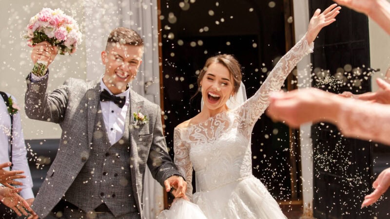 Couple on wedding day leaving church with confetti