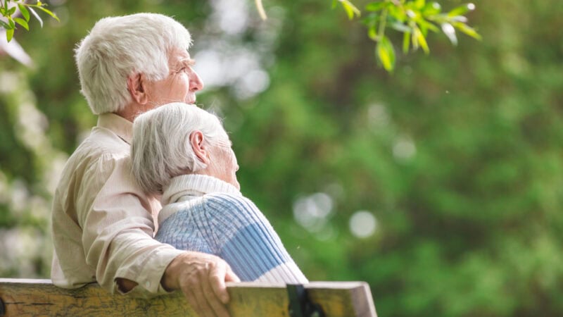Elderly couple sat on park bench